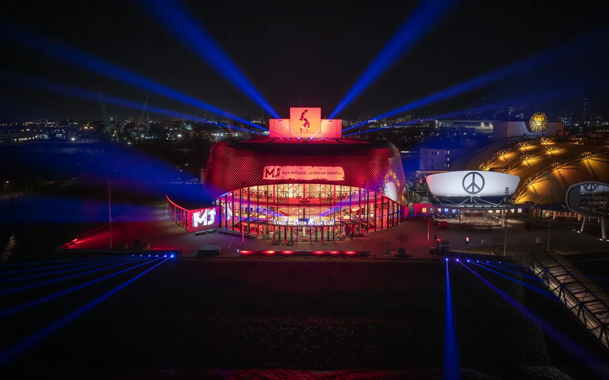 Beleuchtetes Theater an der Elbe bei Nacht mit Lichtsäulen am Himmel