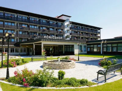 Außenansicht des Kurhotels Königshof mit Garten und Springbrunnen.
