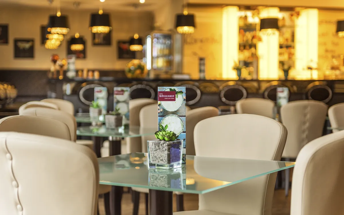 Barbereich im Königshof Bad Füssing mit Tischen und moderner Beleuchtung.