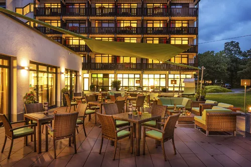 Terrasse eines Hotels mit Tischen und Stühlen in Bad Füssing am Abend