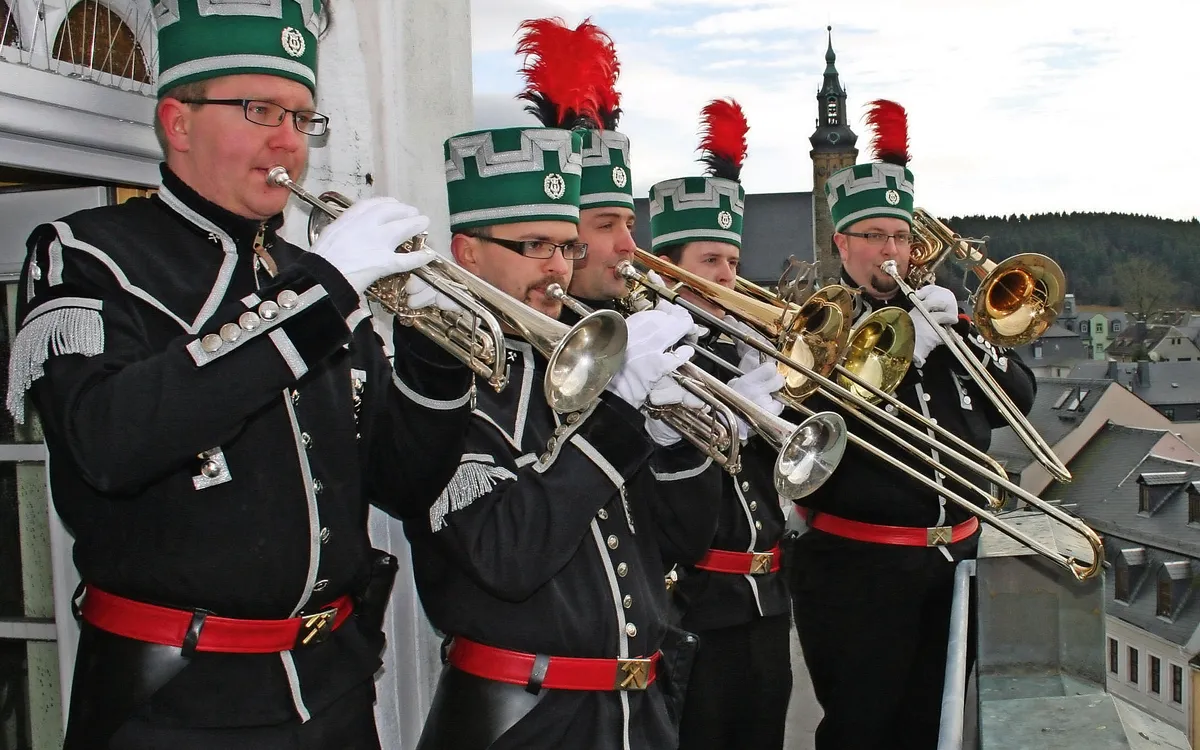 Musiker in Bergmannsuniformen spielen Trompeten auf einem Balkon in Schneeberg.