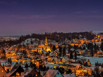 Winterliche Nachtansicht von Seiffen im Erzgebirge mit beleuchteten Häusern im Schnee.