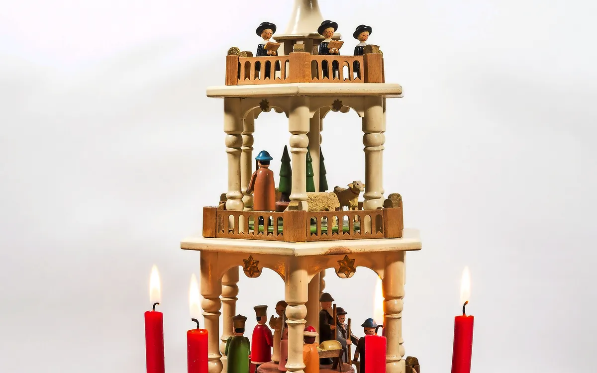 Handgefertigte mehrstöckige Weihnachtspyramide aus Holz mit roten Kerzen.