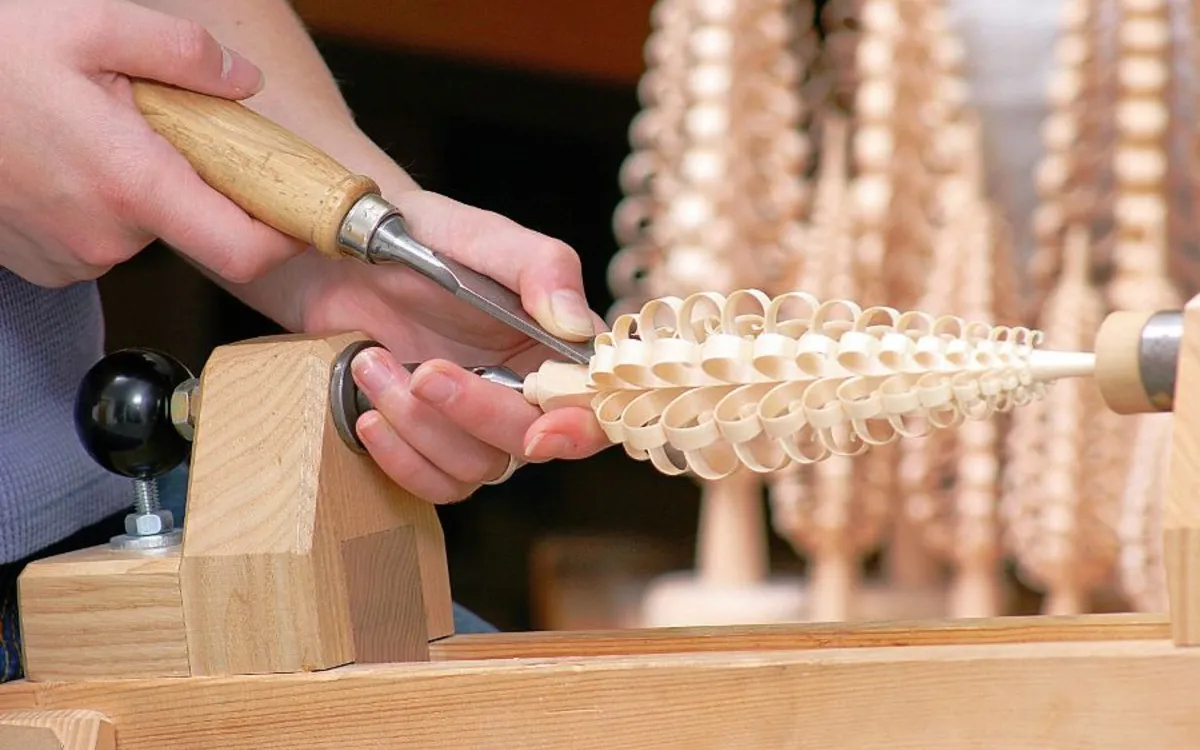Hände schnitzen einen traditionellen Spanbaum aus Holz.