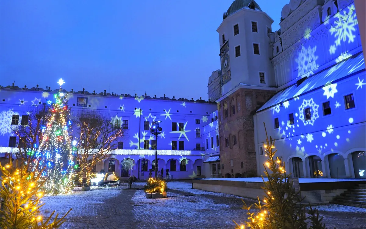 Weihnachtlich geschmückter Innenhof mit Lichterdekoration und Projektionen von Schneeflocken.