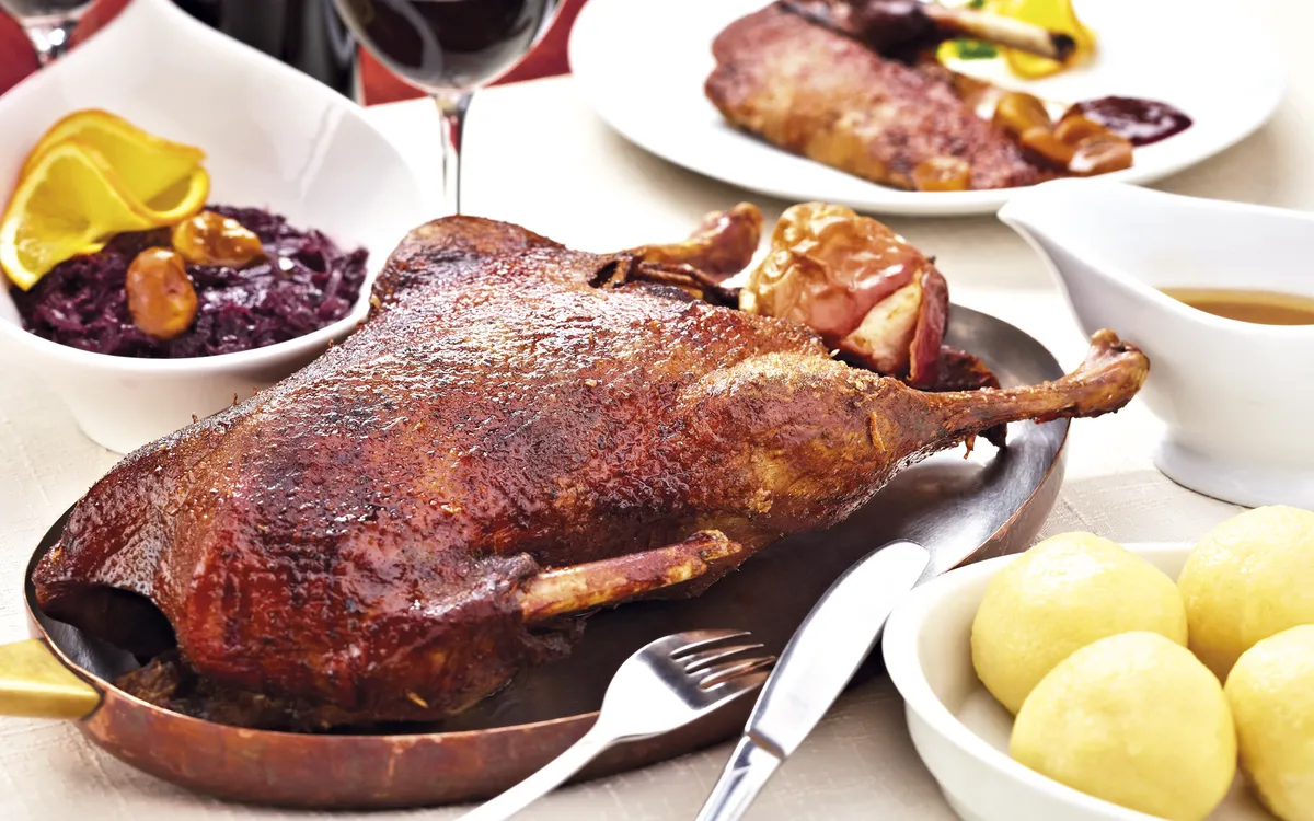 Knuspriger Gänsebraten mit Rotkraut und Kartoffelknödel auf einem festlichen Teller.