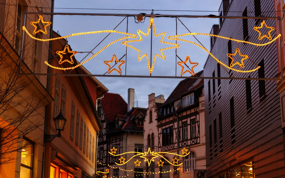 Straße mit weihnachtlicher Beleuchtung und Fachwerkhäusern bei Dämmerung.