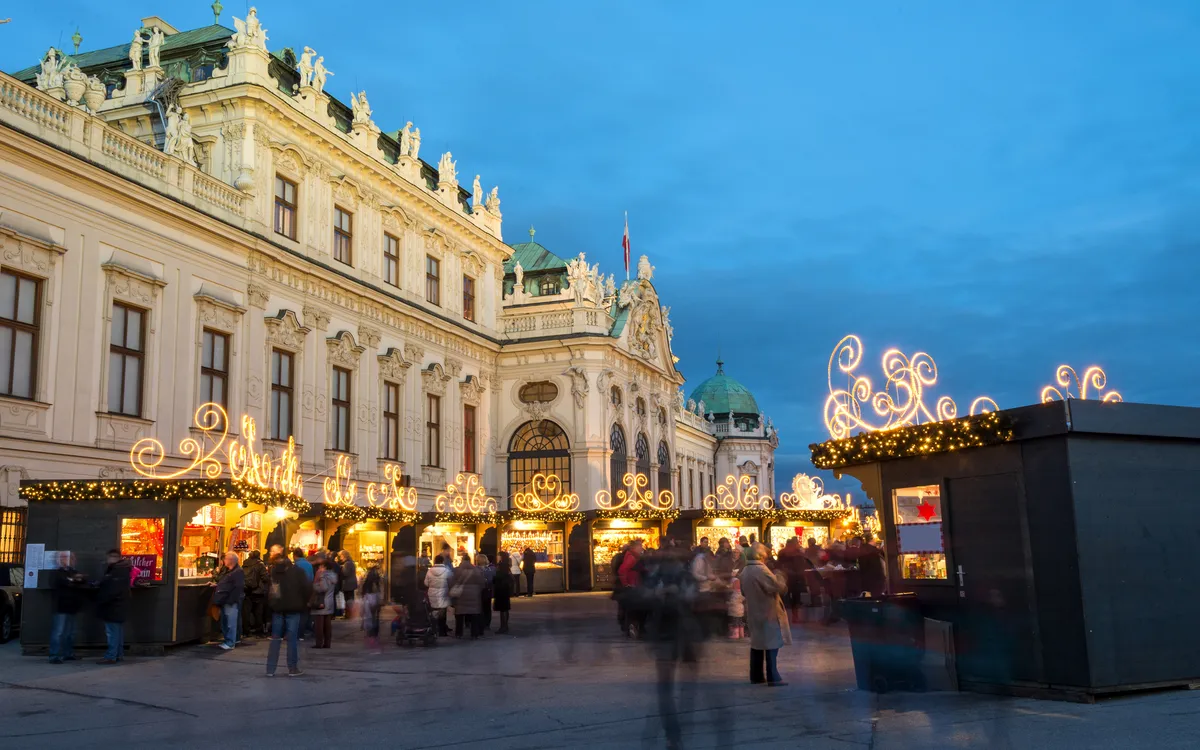 Weihnachtsmarkt vor einem historischen Gebäude in der Abenddämmerung.