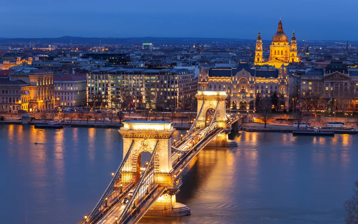 Stadtansicht bei Nacht mit beleuchteter Brücke und Kirche im Hintergrund