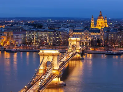 Stadtansicht bei Nacht mit beleuchteter Brücke und Kirche im Hintergrund
