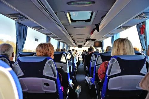 Innenansicht eines fahrenden Reisebusses mit sitzenden Fahrgästen.