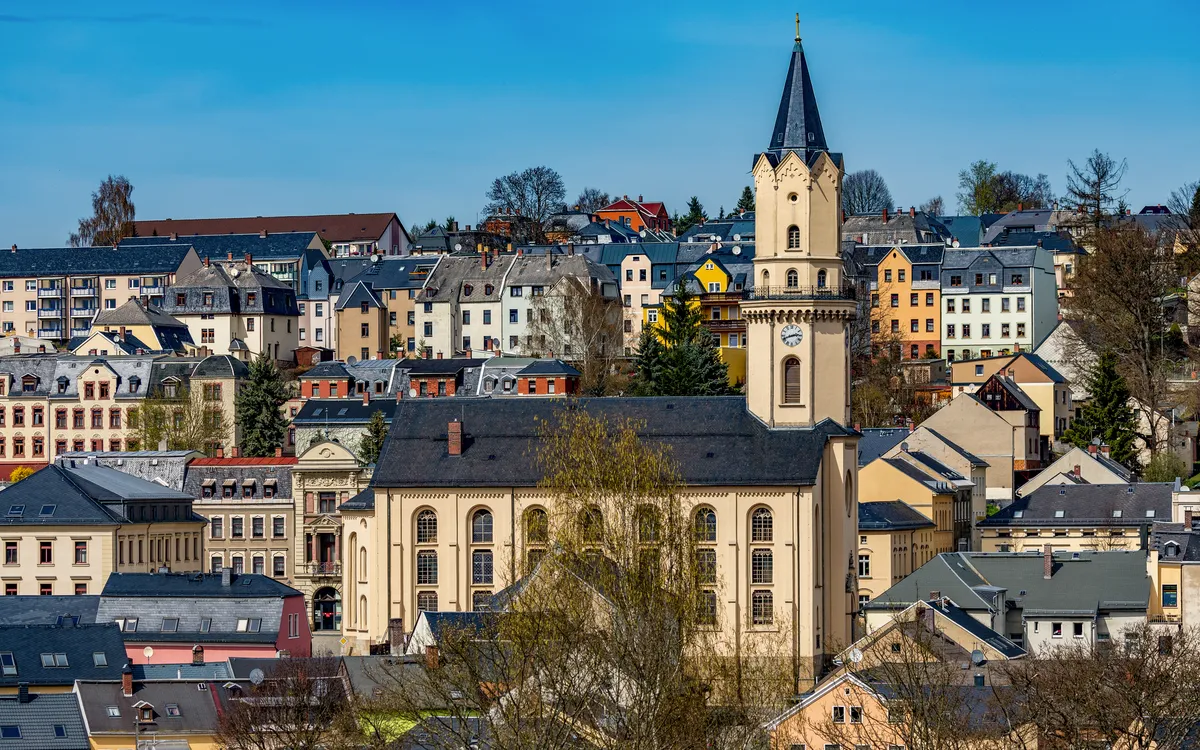 Panorama einer Stadt mit Kirche und umliegenden Häusern im Sonnenschein.