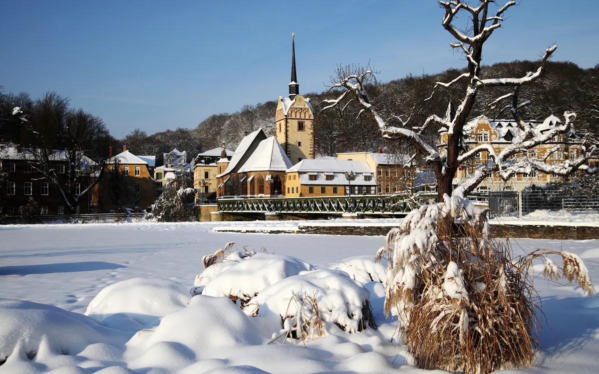 Schneebedeckte Landschaft mit Kirche und Dorf im Hintergrund.