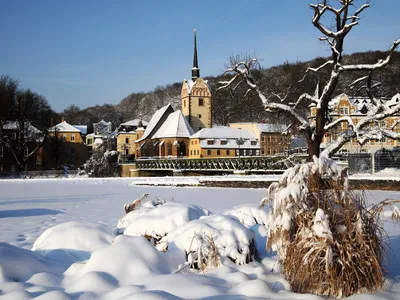 Schneebedeckte Landschaft mit Kirche und Dorf im Hintergrund.