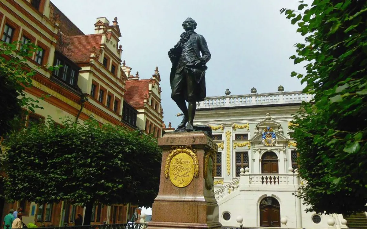 Bronzestatue von Goethe auf einem Sockel vor einem historischen Gebäude.