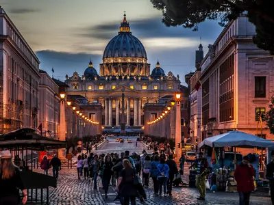 Nachtansicht der beleuchteten Basilika St. Peter in Rom auf dem Petersplatz bei Dämmerung.