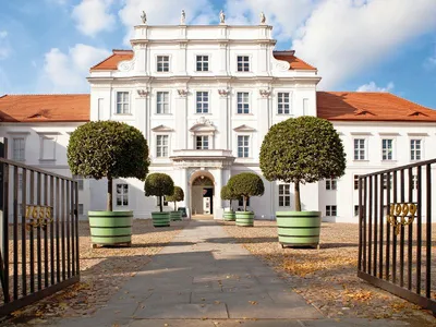Barocke Fassade von Schloss Oranienburg mit Einfahrt und Tor im Vordergrund.