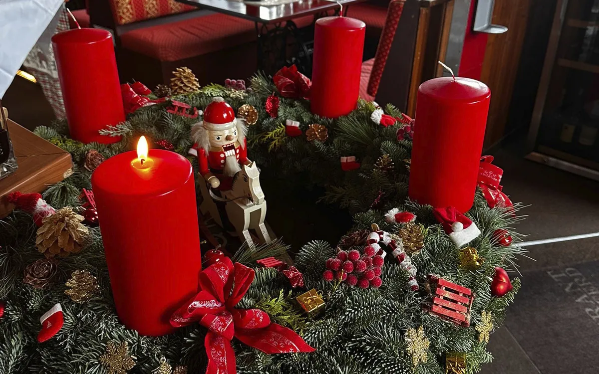 Weihnachtlich dekorierter Tisch mit Adventskranz und roten Kerzen.