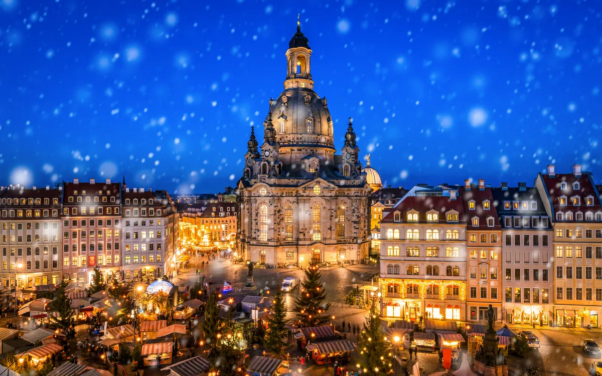 Weihnachtsmarkt vor der beleuchteten Frauenkirche, Neumarkt Dresden bei Schnee.