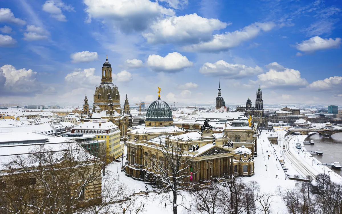 Verschneite Dresdner Frauenkirche und Elbe im Winter.