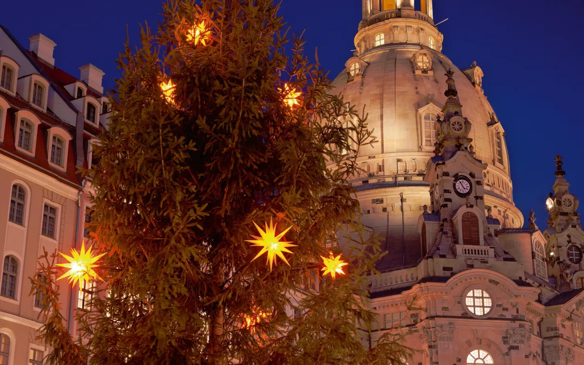 Weihnachtsmarkt vor der beleuchteten Frauenkirche in Dresden bei Nacht.