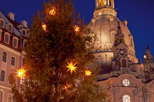 Weihnachtsmarkt vor der beleuchteten Frauenkirche in Dresden bei Nacht.