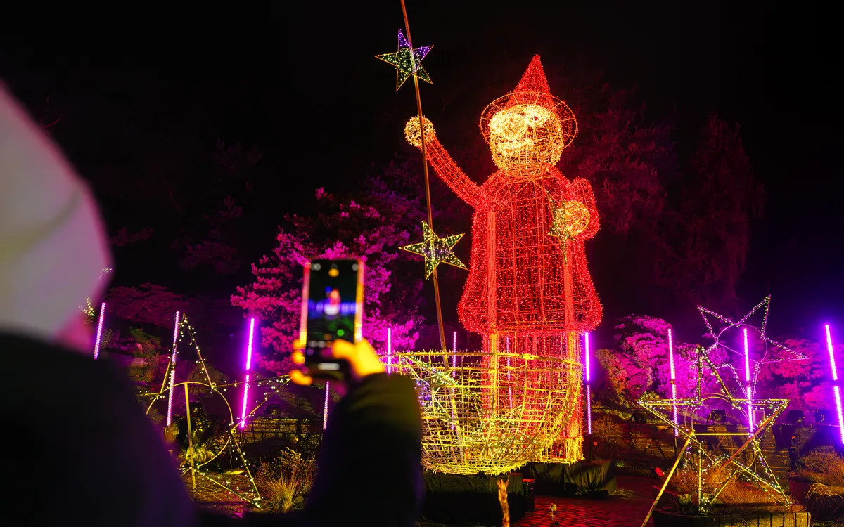 Leuchtende Figur eines Zauberers bei Nacht im Christmas Garden Hamburg.