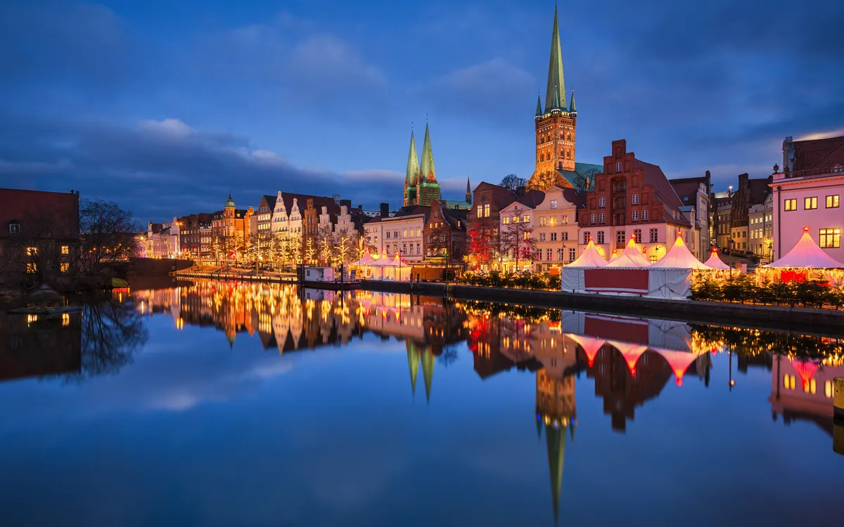 Weihnachtsmarkt in Lübeck vor dem Holstentor bei Abenddämmerung.