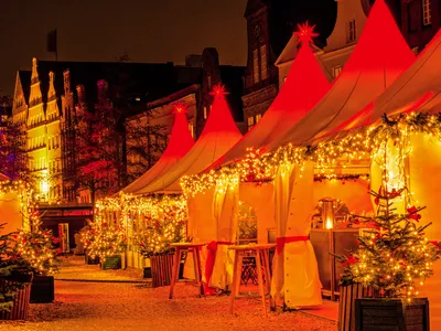 Weihnachtsmarkt in Lübeck mit Lichterketten bei Nacht entlang des Flusses.