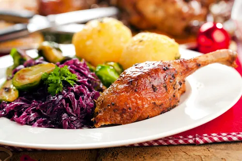 Gänsekeule mit Rotkohl und Kartoffelklößen auf festlichem Teller.