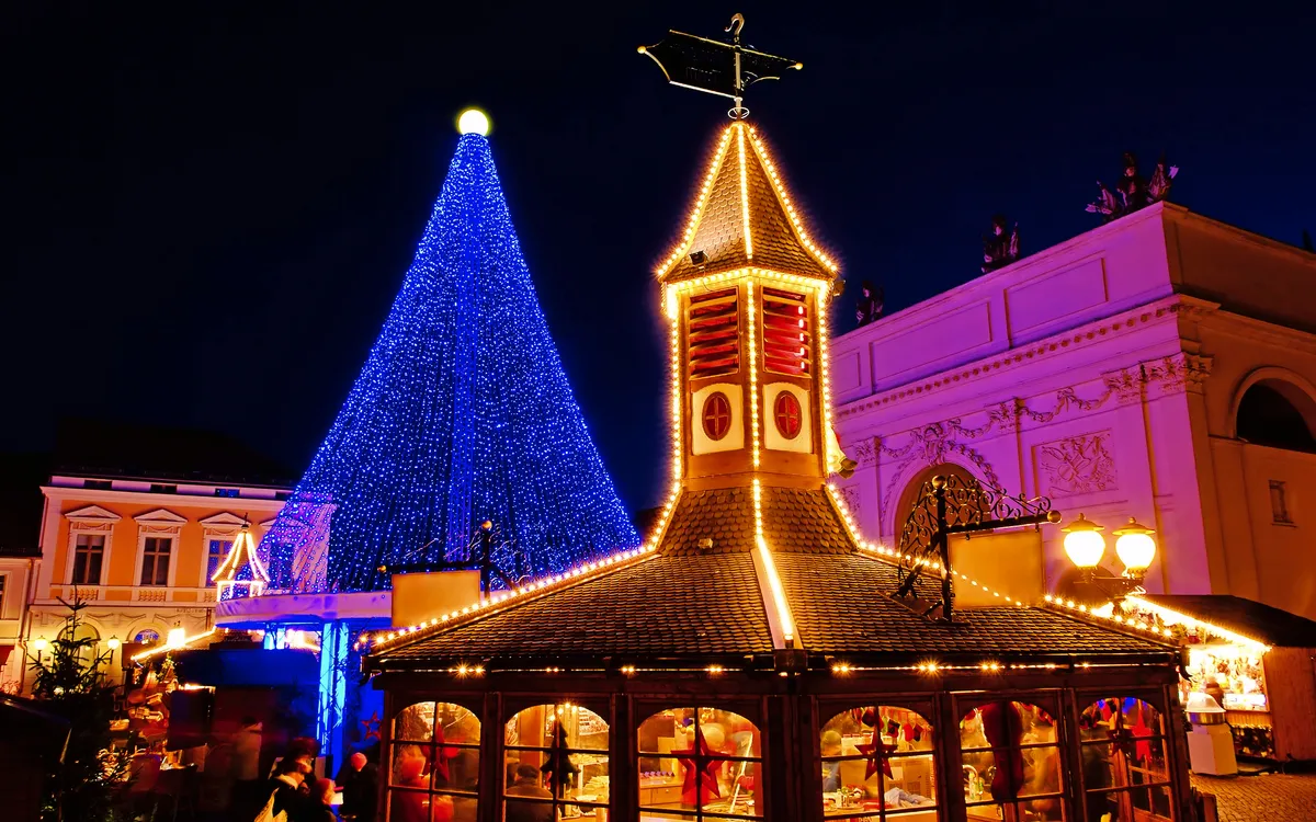 Potsdamer Weihnachtsmarkt mit beleuchtetem Baum und Pyramide bei Nacht.