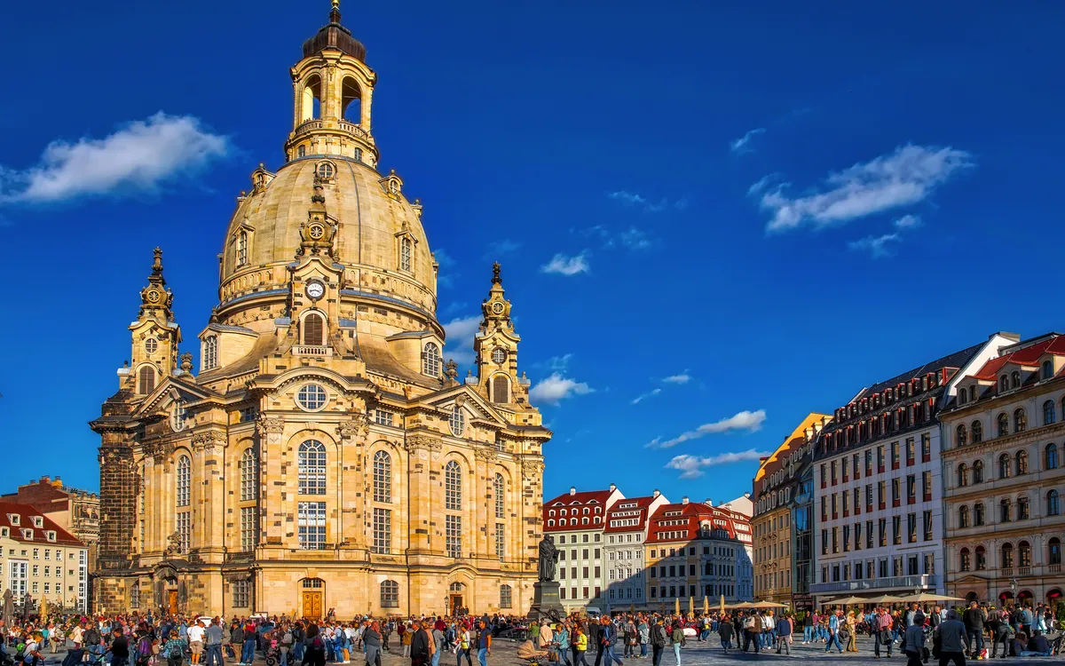Frauenkirche Dresden mit blauem Himmel und Menschen auf dem Platz.