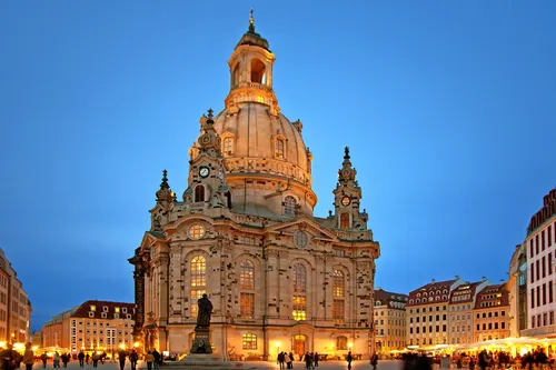Frauenkirche Dresden bei Abenddämmerung, beleuchtetes Gebäude mit Menschen auf dem Platz.