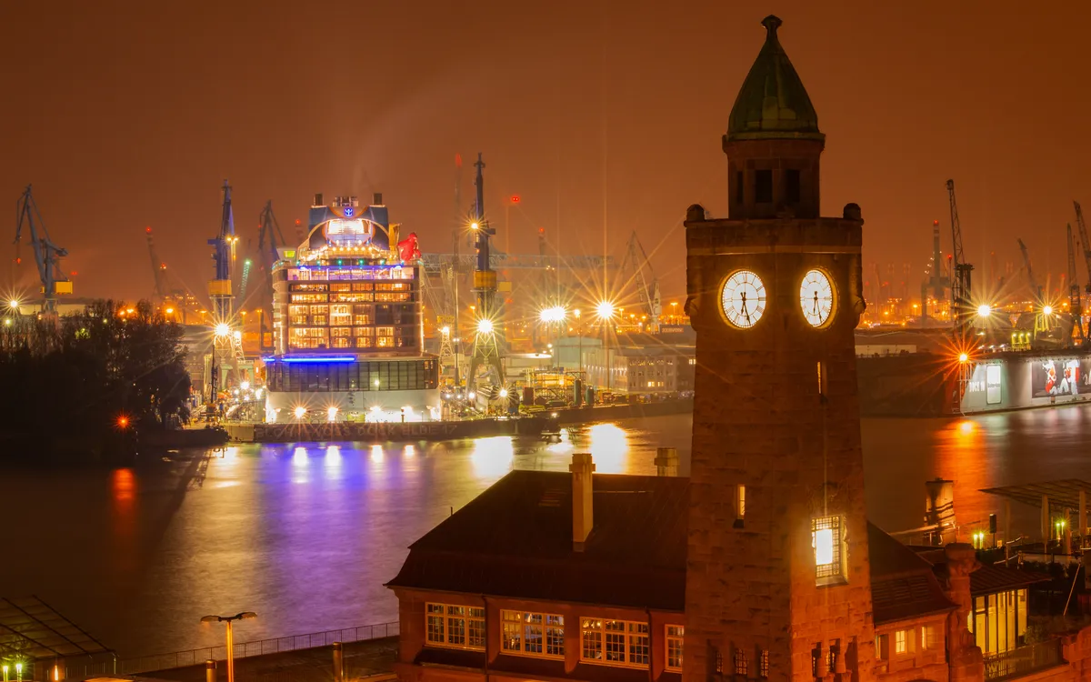 Nachtaufnahme der beleuchteten St. Pauli Landungsbrücken mit Kränen in Hamburg.