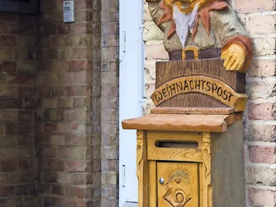 Postkasten mit Weihnachtsmannfigur an Backsteinwand.