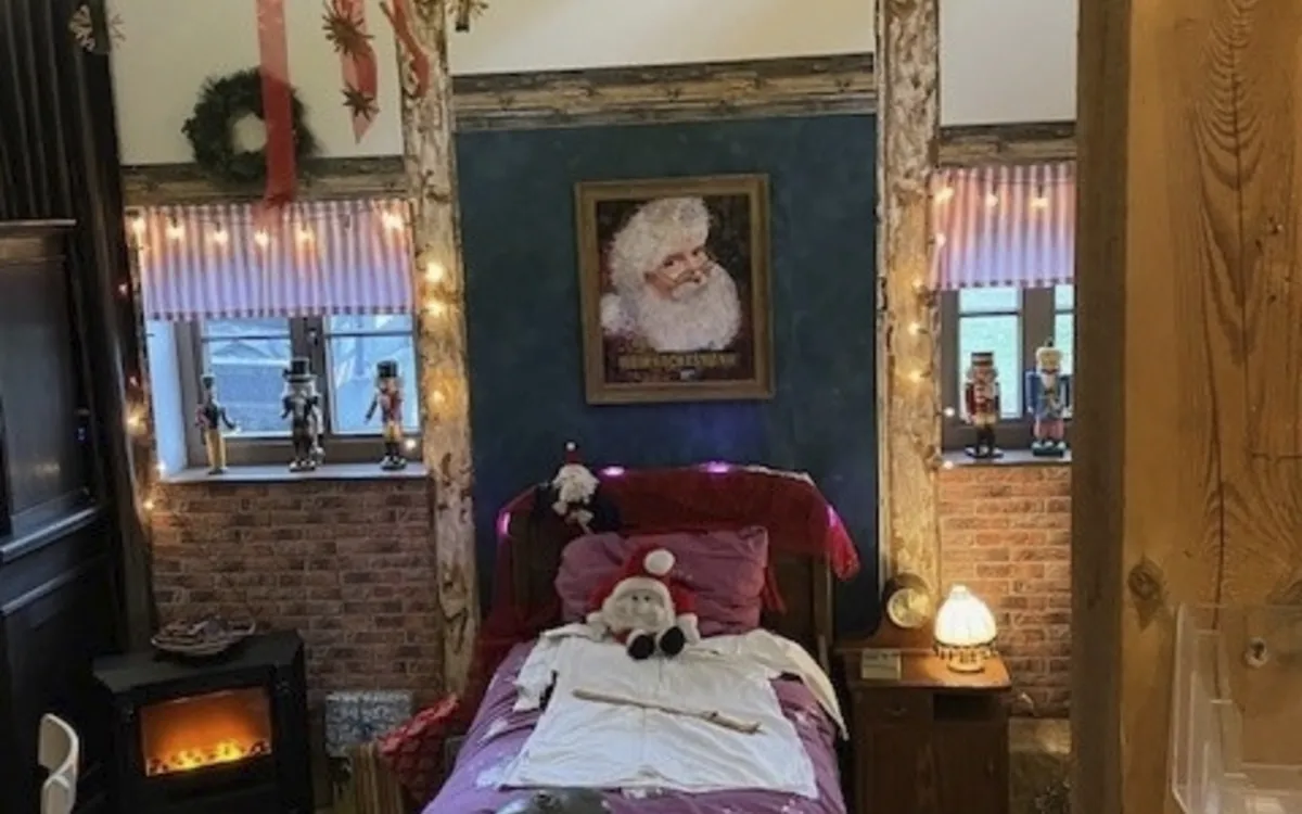 Gemütliches Zimmer mit Weihnachtsdekoration und Bild vom Weihnachtsmann an der Wand.