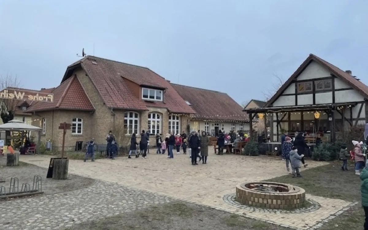 Historisches Backsteinhaus mit Weihnachtsmarkt, Menschen spazieren außen.