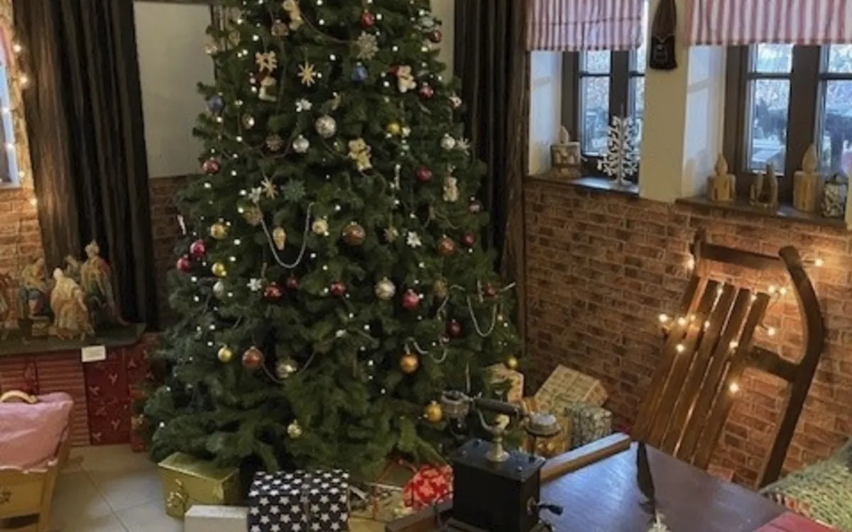 Weihnachtlich dekorierter Raum mit geschmücktem Tannenbaum und Geschenken.