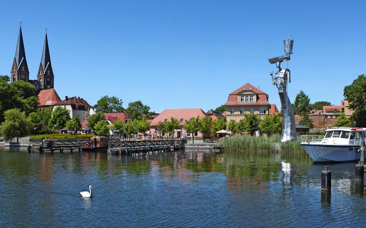 Stadtansicht von Neuruppin am Ruppiner See mit Kirche und Bootsanleger.