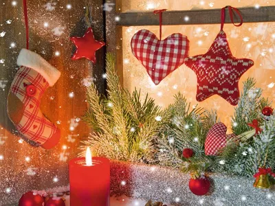 Weihnachtliche Dekoration mit Kerze, Tannenzweigen, Sternen und Nikolausstiefel am Fenster.