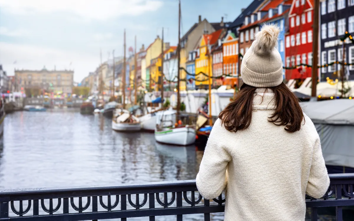 Frau genießt winterliche Aussicht auf Nyhavn in Kopenhagen, Dänemark.