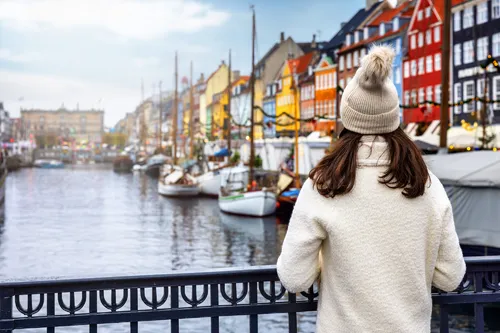 Frau genießt winterliche Aussicht auf Nyhavn in Kopenhagen, Dänemark.