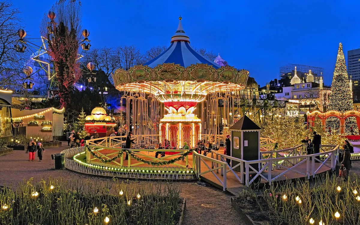 Weihnachtlich beleuchtetes Karussell im Tivoli in Kopenhagen abends im Winter.