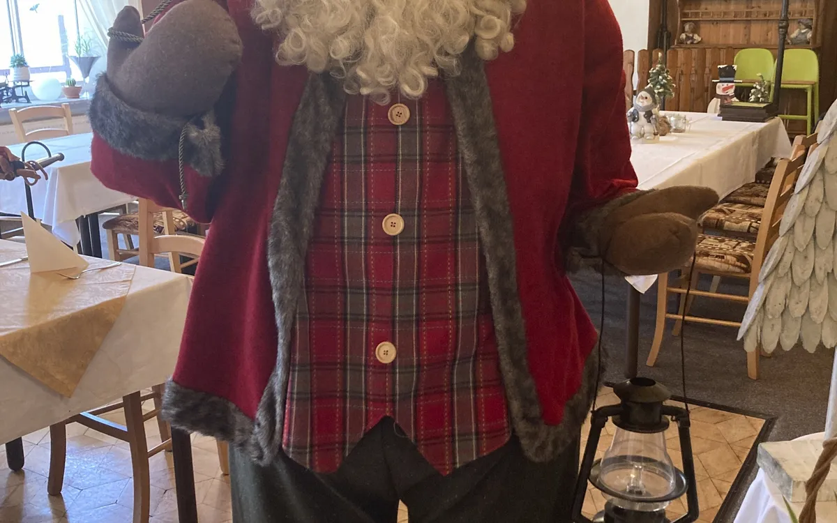 Weihnachtsmannfigur in rustikalem Raum mit Tischdekorationen.