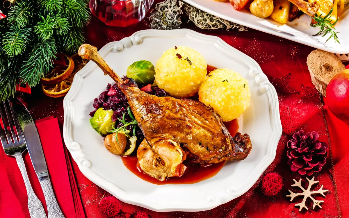 Weihnachtsgans mit Klößen und Rosenkohl auf einem festlichen Teller.