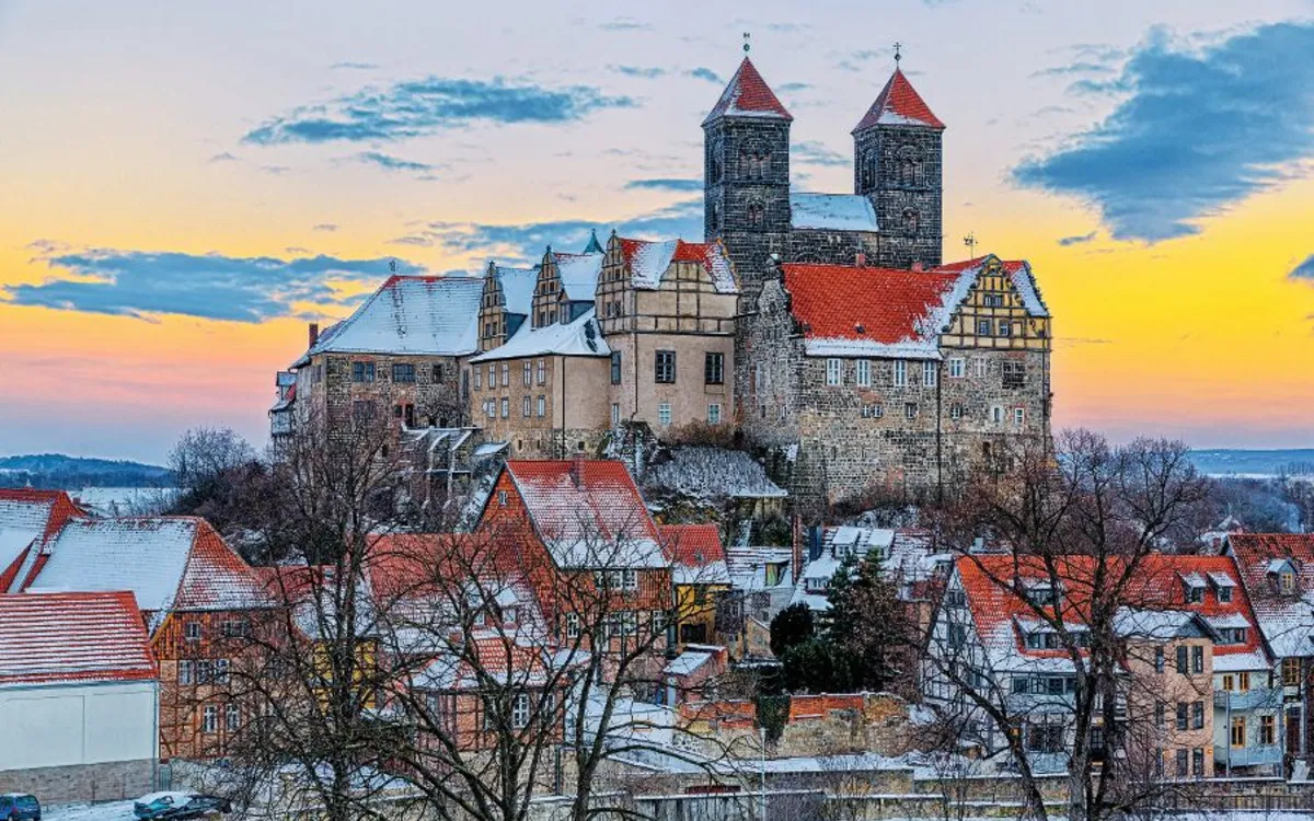 Schloss und Altstadt im Winter bei Sonnenuntergang mit Schnee auf den Dächern.