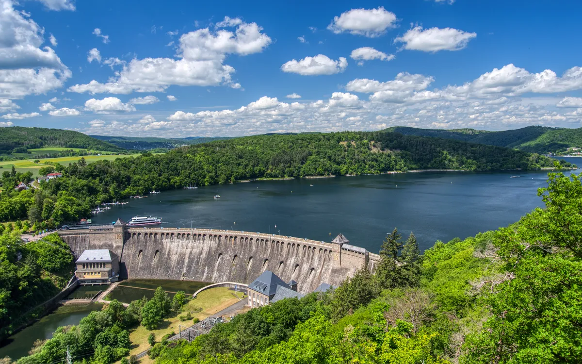 Staumauer einer Talsperre mit umliegender Landschaft und blauem Himmel