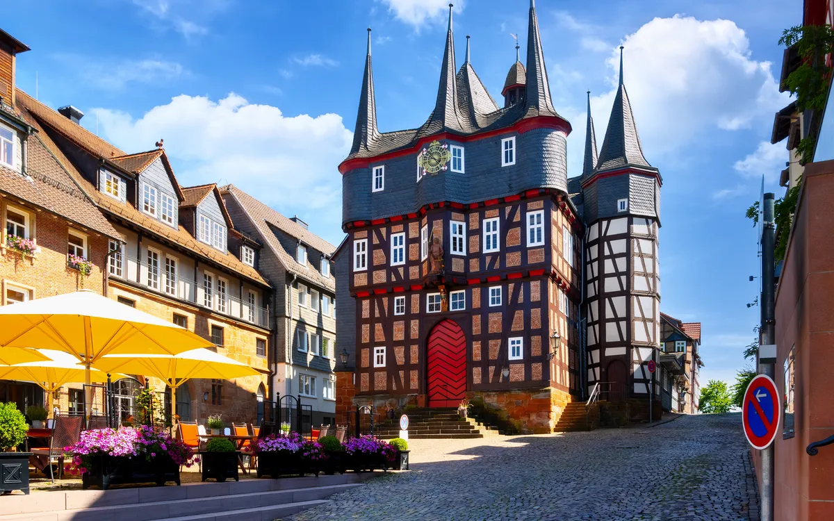 Lebhaftes Fachwerkhaus mit Türmen und sonnigem Marktplatz.