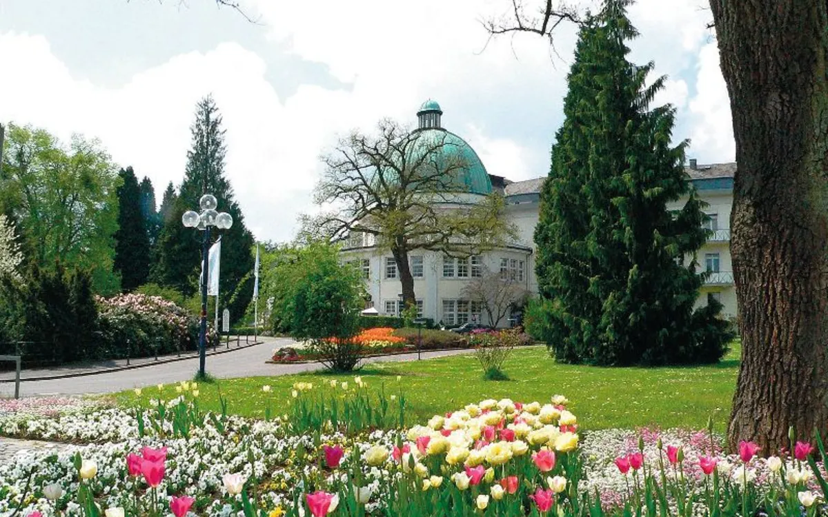 Kurpark mit Blumenbeeten vor dem Badehotel Maritim, Kuppeldach im Hintergrund.