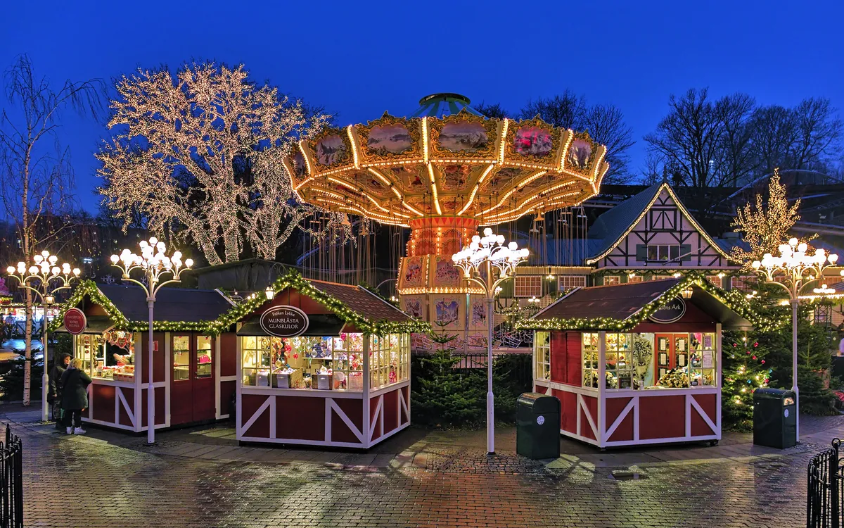 Weihnachtsmarkt mit beleuchtetem Karussell im Vergnügungspark Liseberg, Göteborg.